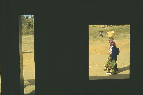 10008059. KENYA Voi Women carrying baskets framed by window of building in deep shadow