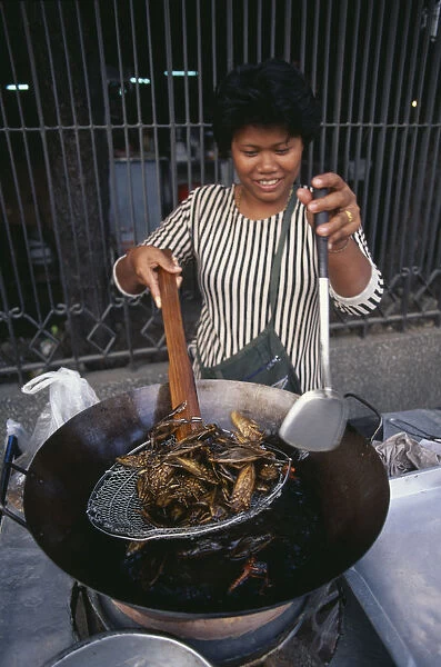 10051867. THAILAND Bangkok Woman cooking insects in a wok at a market stall