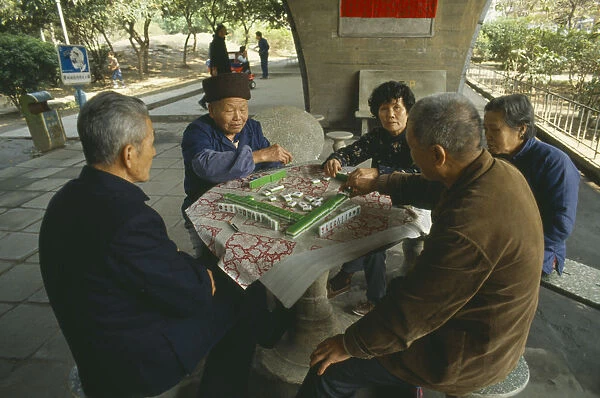 10063504. CHINA Guangzhou Men and women sat around table playing Mahjong