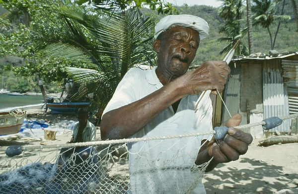 10078805. WEST INDIES St.Lucia Soufriere Fisherman mending nets on the beach
