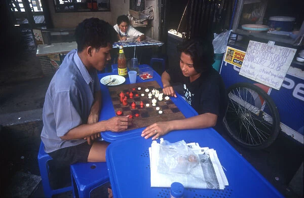 20008860. THAILAND Bangkok Couple playing a board game at a streetside cafe