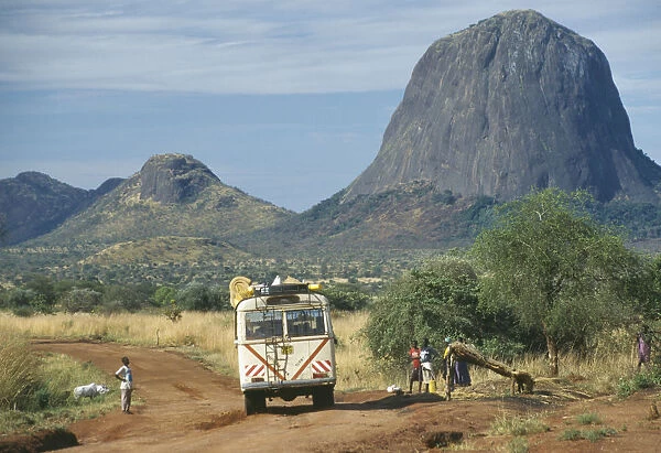20046147. UGANDA Karamoja Minibus travelling along dirt road with people at the side