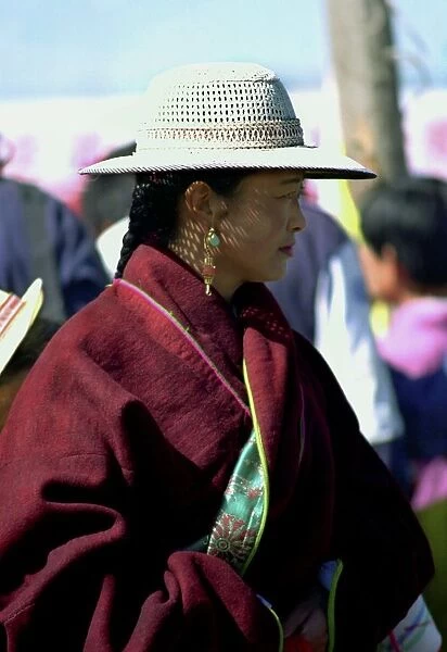 20046270. CHINA Gansu Xiahe Lady watching festival wearing a hat