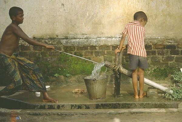 20047093. BANGLADESH Chittagong Shamshangar Two young boys drawing water from rowerpump