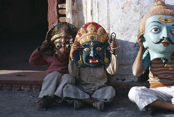 20061257. INDIA Festival Small children sitting in street wearing huge masks