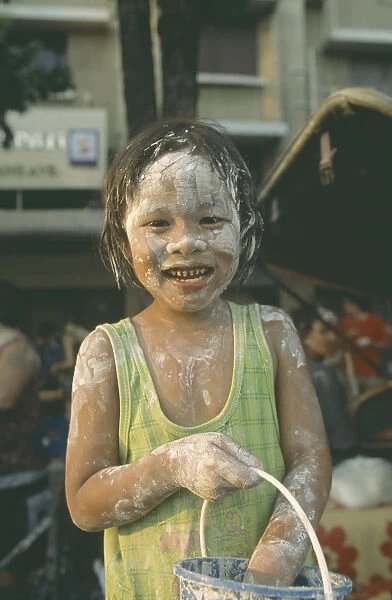 20072423. THAILAND Bangkok Young girl with bucket covered in mud at the Songkhran Festival