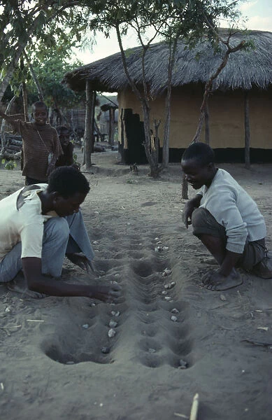 20076481. ZAMBIA Ukwimi Settlement Mozambique refugees playing game of solo. mancala bao