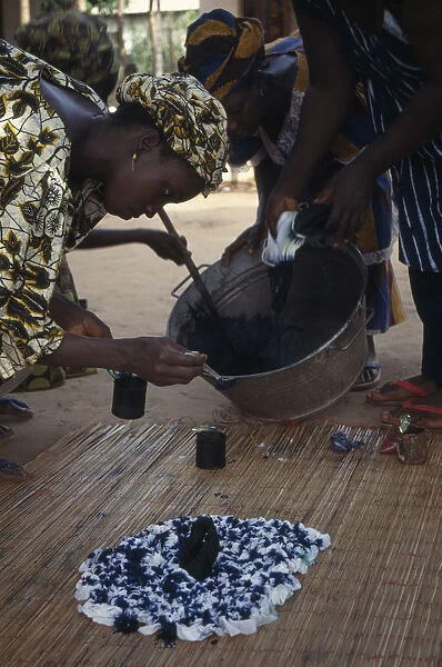 20076573. GAMBIA Arts Woman applying indigo dye to cloth during tie dye process