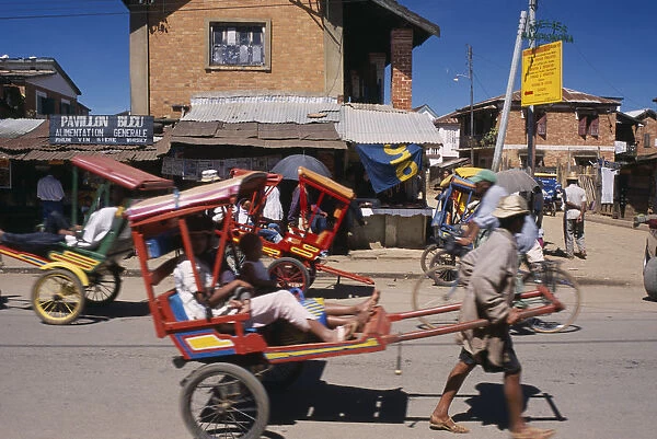 20079229. MADAGASCAR Antsirabe Rickshaws with passengers traveling along road