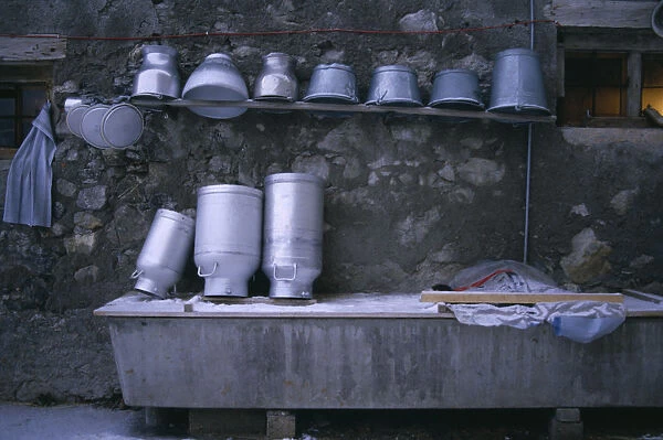 20079672. SWITZERLAND Agriculture Washed milk churns and pails on shelf above trough
