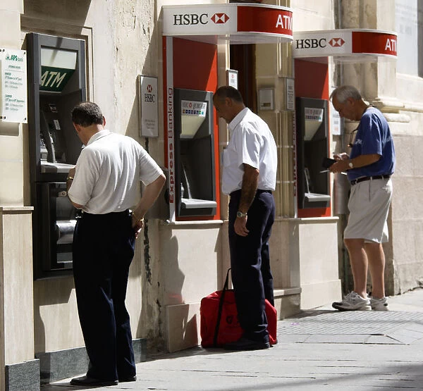 20090326. MALTA Valletta Three men using separate ATM cash machines on Republic Street