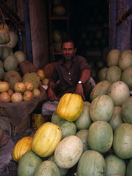 BANGLADESH, Dhaka Man selling durians and melons in fruit market