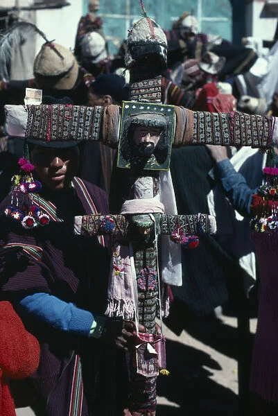 BOLIVIA, Macha Tingku Festival Day. Man holding a large decorated cross with the face