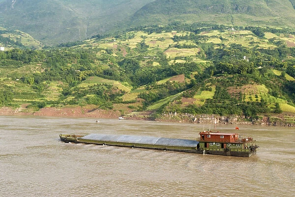 China, Chongqing, Wushan Barge on the Yangtze River near Wushan passing rich farmland