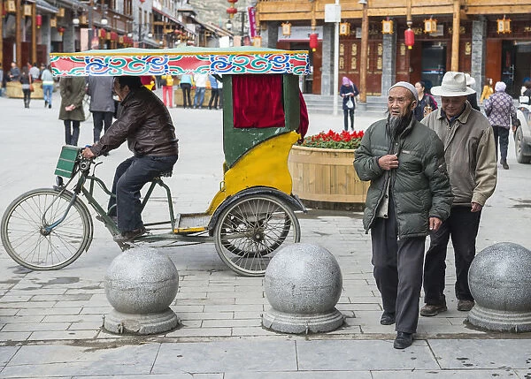 China, Sichuan, Songpan, Yawning trishaw driver and walking aged citizens