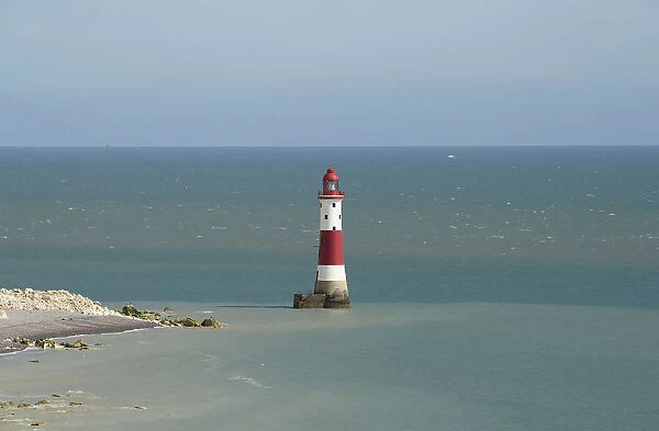 England, East Sussex, Beachy Head, Red and white painted lighthouse at base of cliffs