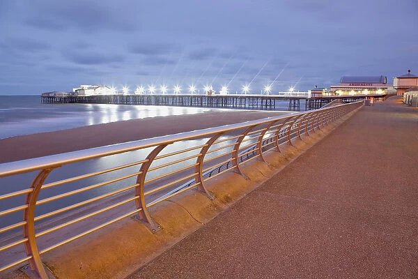England, Lancashire, Blackpool, Seafront promenade with North Pier illuminated at dusk