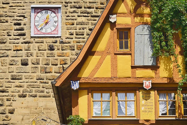 Germany, Bavaria, Rothenburg ob der Tauber, Facade of a colourful half timbered house with a clock on the wall