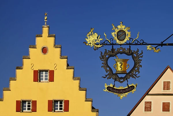 Germany, Bavaria, Rothenburg ob der Tauber, Detail of colourful building on Marktplatz with wrought iron sign in foreground