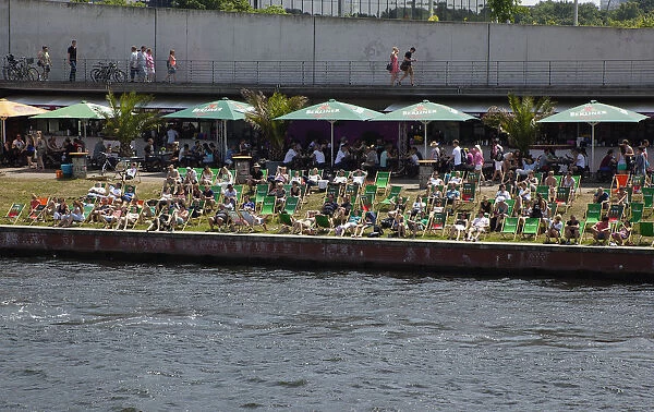 Germany, Berlin, Mitte, people sunbathing on the banks fo the river Spree