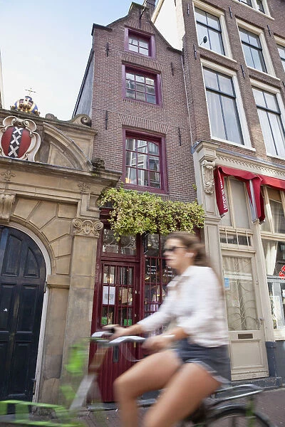 Holland, North, Amsterdam, Typical Dutch gable buildings with blurred girl cyclist