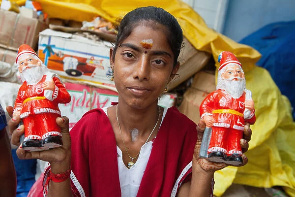 India, Pondicherry, Portait of a girl holding figurines of Father Christmas