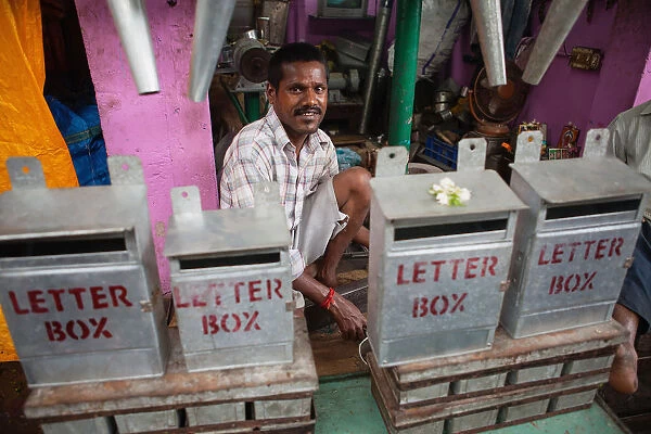 India, Pondicherry, Tinker behind a display of metal letter boxes