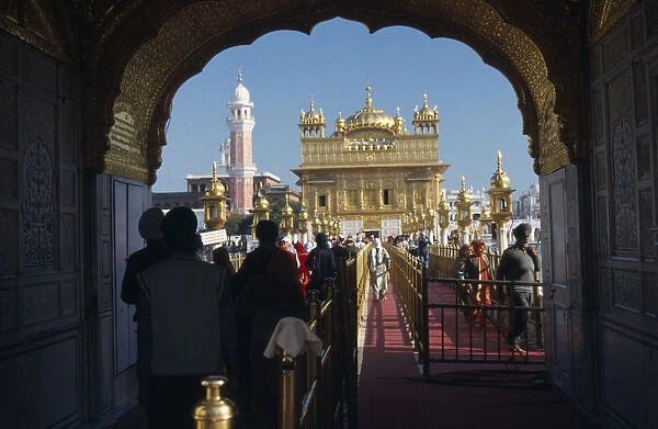 INDIA, Punjab, Amritsar Entrance arch to the Golden Temple with people walking along