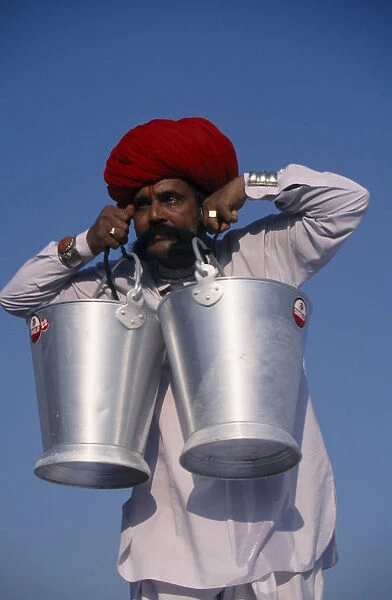 INDIA, Rajasthan, Bikaner Rajput man lifting buckets of water with his moustache