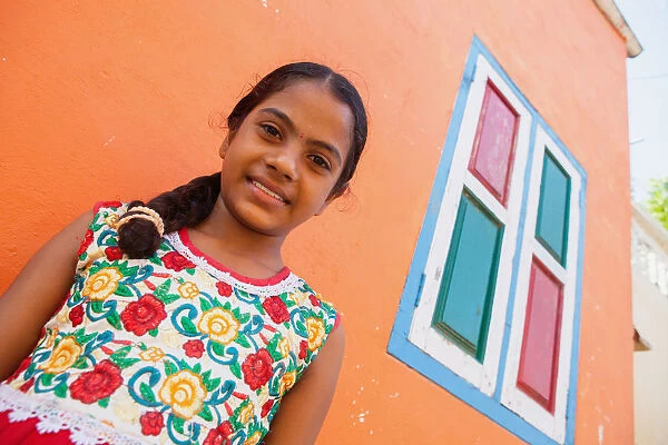 India, Tamil Nadu, Mahabalipuram, Portrait of a Tamil girl standing outside her orange painted home in Mahabalipuram