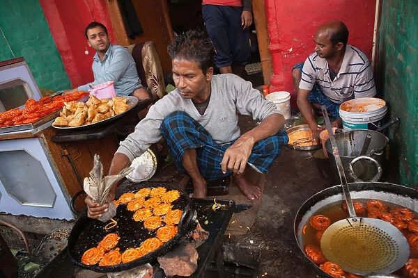 India, Uttar Pradesh, Faizabad, A cook frying jalebis at a food hotel