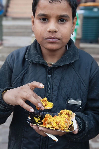 India, Uttar Pradesh, Varanasi, A boy eats street food