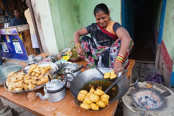 India, Uttar Pradesh, Varanasi, A woman cooking fried pakora and samosas at a food hotel