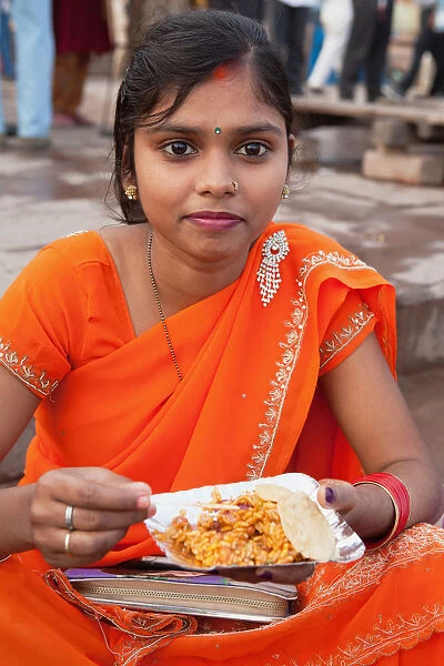 India, Uttar Pradesh, Varanasi, A woman eats a snack of bhel puri & kachori on the ghats