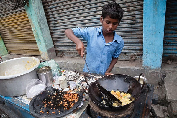 India, West Bengal, Asansol, A boy fries chilli pakora on a street food cart