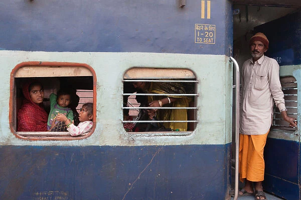 India, West Bengal, Asansol, Passengers at the window & footplate of a train carriage at railway station
