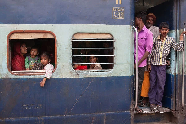 India, West Bengal, Asansol, Passengers at the window & footplate of a train carriage at railway station