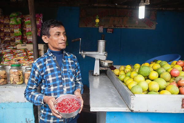India, West Bengal, Asansol, Portrait of a juice vendor holding a bowl of pomegranate seeds