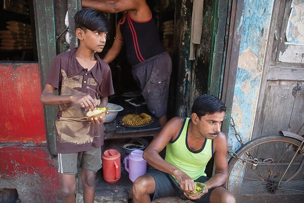 India, West Bengal, Kolkata, A man and boy eat a snack of pani puri and vegetables