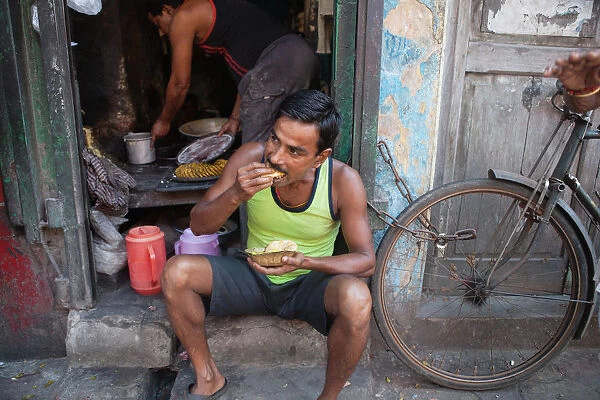 India, West Bengal, Kolkata, A man eating a snack of pani puri and vegetables