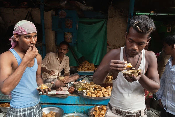 India, West Bengal, Kolkata, Men eat samosas and kachori