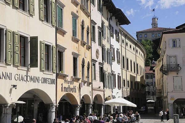 Italy, Friuli Venezia Giulia, Udine, cafes lined along Piazza Mateotti with Castle above
