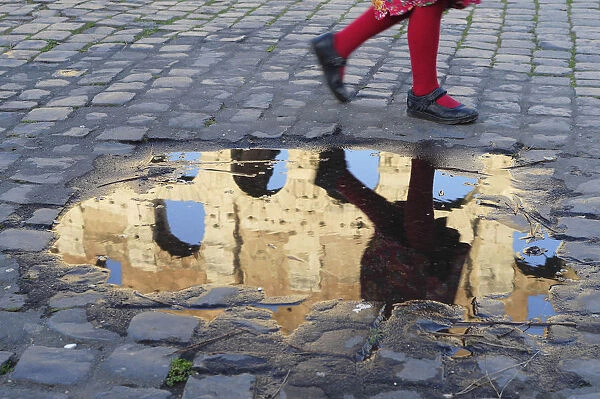 Italy, Lazio, Rome, Colosseum, girl running past puddle with reflection of the Colosseum