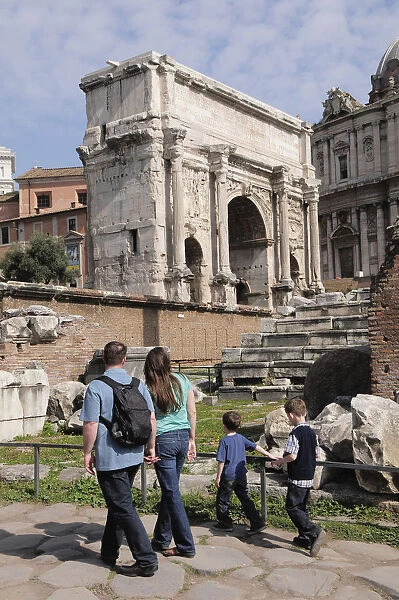Italy, Lazio, Rome, Roman Forum, Foro Romano, Arch of Septimus Severus with family walking along cobbled road