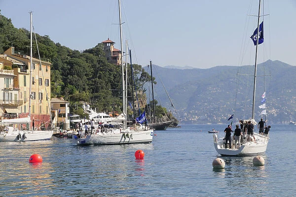 Italy, Liguria, Portofino, waterside houses with sailing boat leaving the bay