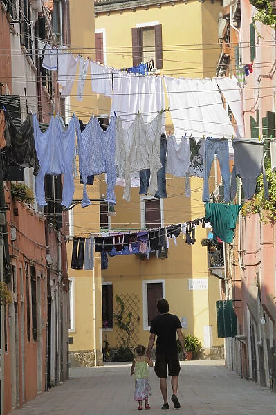 Italy, Veneto, Venice, Arsenale, narrow strees with washing & child & father walking