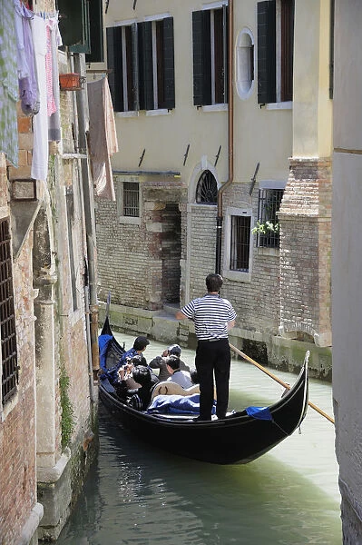 Italy, Veneto, Venice, gondola passing through narrow canal in Arsenale