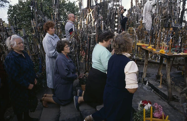 LITHUANIA, Hill of Crosses Men and women pray in front of hundreds of crosses