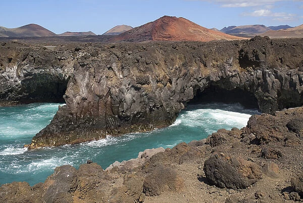 Los Hervideros or Boiling Waters from viewpoint on south west coast road. The sea crashes through lava formed tunnels sea eroded chimneys and arches as if boiling