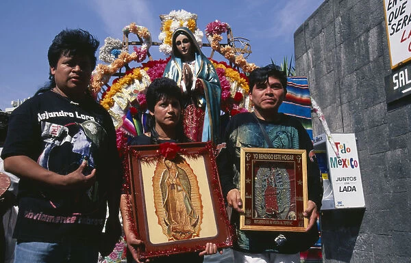 MEXICO, Mexico City Pilgrims carrying icons and standing in front of statue of the